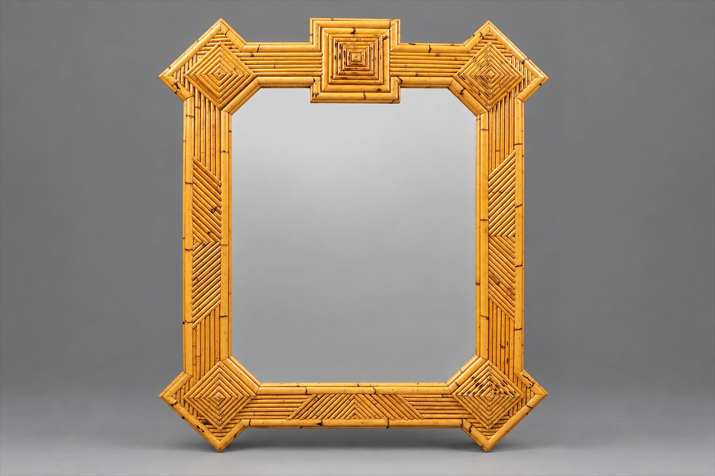 Honey-toned bamboo marquetry mirror with geometric motifs, diamond-shaped corner ornaments and a raised square crest, about 1970